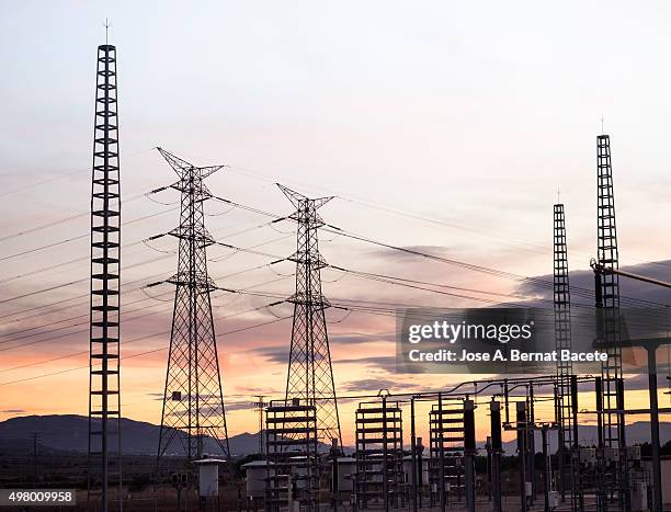 electrical towers and power lines in sunset - maquinaria photos et images de collection