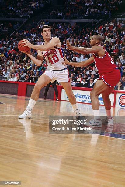 Bill Laimbeer of the Detroit Pistons passes the ball against Charles Barkley of the Philadelphia 76ers circa 1990 at the Palace of Auburn Hills in...