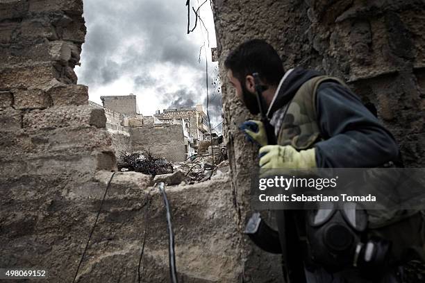 Free Syrian Army fighter observes the damage and smoke rising from a civilian neighborhood after being targeted by a Syrian Army artillery strike....