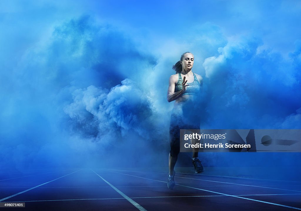 Athlete running through blue smoke