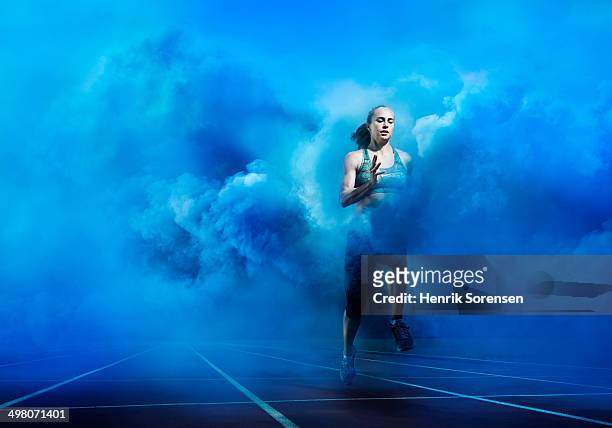 athlete running through blue smoke - running motivation stock pictures, royalty-free photos & images