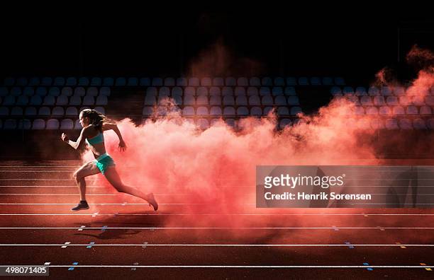 athlete running in red smoke - motivazione foto e immagini stock