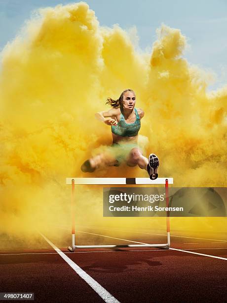 athlete over hurdle in yellow smoke - colored smoke stock-fotos und bilder