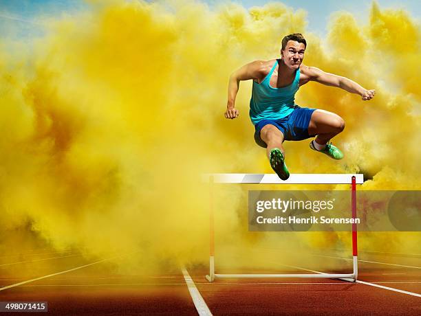 athlete over hurdle, in yellow smoke - hurdle stock pictures, royalty-free photos & images