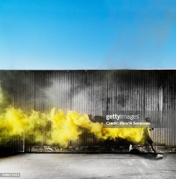 athlete running in yellow smoke - yellow smoke stock pictures, royalty-free photos & images