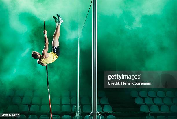 athlete jumping pole vault in smoke - stabhochsprung stock-fotos und bilder