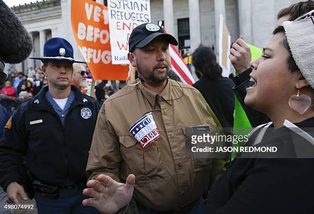 Man blocks supporters of refugees as they counter-protest an anti-refugee group gathered on the steps of the state capitol to protest Gov. Jay...