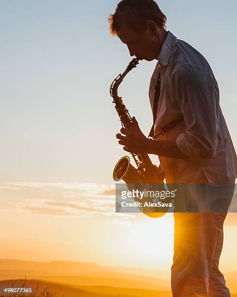 young man playing saxophone outdoor at sunset - saxophonist stock pictures, royalty-free photos & images