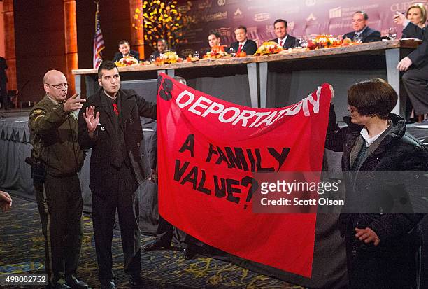 Immigrant rights protestors raise a banner after jumping a security barricade at the Presidential Family forum as Republican presidential candidates...