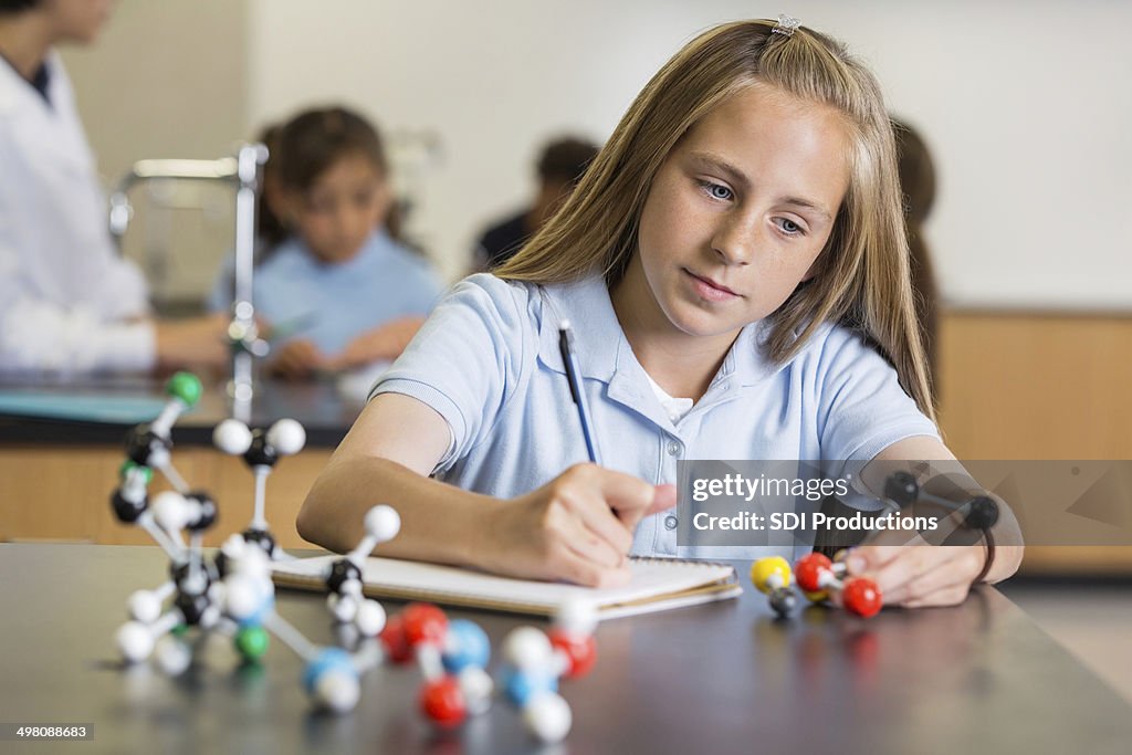 Preteen girl using atom educational toy in science class