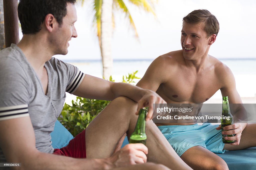 Young men chatting and drinking poolside