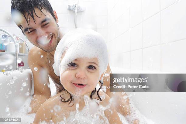 father and baby daughter playing in bath - domestic bathroom stock pictures, royalty-free photos & images
