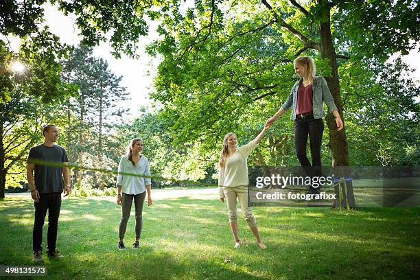 jovem mulher no parque, equilibrando-se em uma slackline - corda bamba - fotografias e filmes do acervo