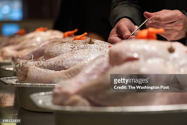 Tim Carman, food writer for The Washington Post via Getty Images, inserts a thermometer into one of several uncooked turkeys during a pop-up timer...