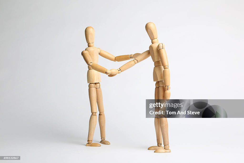 Wooden mannequins shaking hands