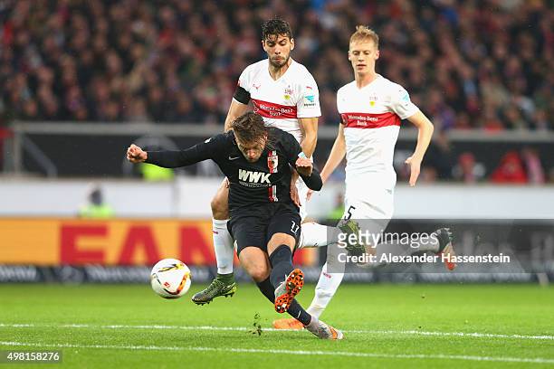 Alexander Esswein of Augsburg scores the opening goal against Emiliano Adrian Insúa Zapata of Stuttgart and his team mate Timo Baumgartl during the...