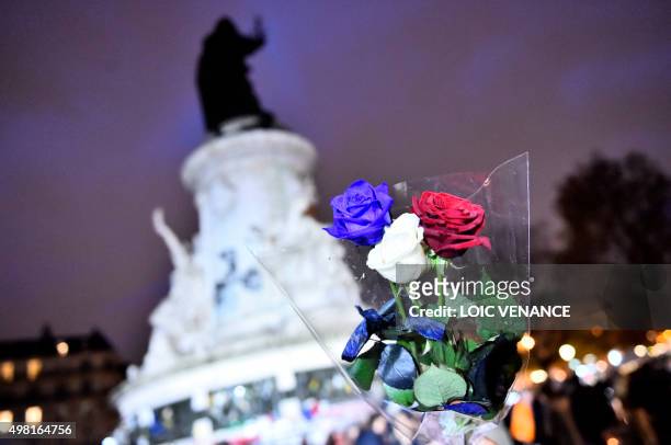 Man holds roses in the colours of the French national flag at Place de la Republique in Paris on November 21, 2015 as he arrives to pay tribute to...