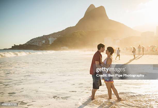 young couple hugging at sunset, ipanema beach, rio, brazil - ipanema beach stock pictures, royalty-free photos & images