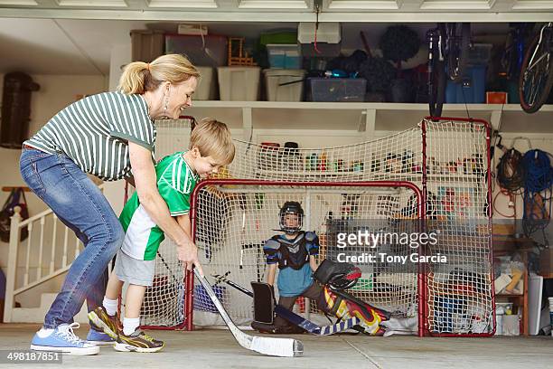 mother playing hockey in garage with two sons - garagentor stock-fotos und bilder