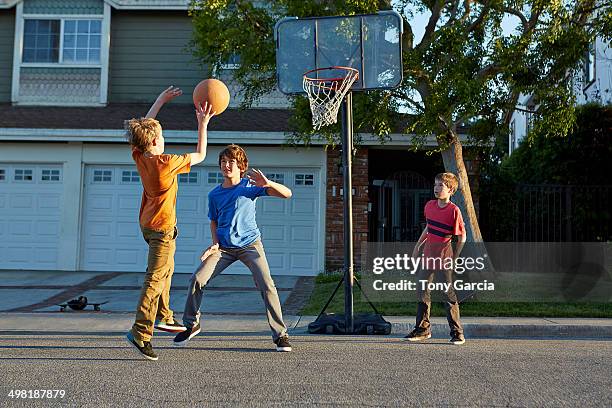 boys playing basketball outside house - street basketball stockfoto's en -beelden