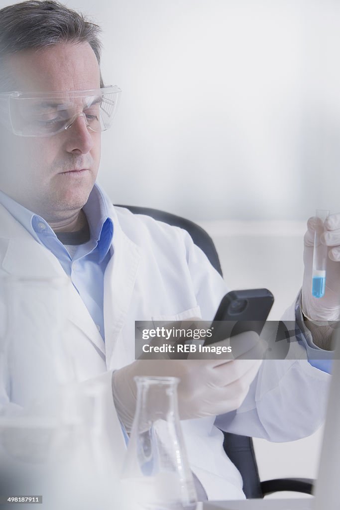 Scientist holding smartphone and test tube