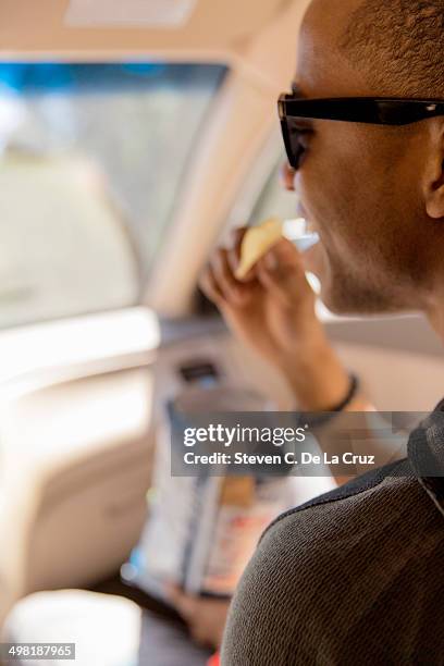 close up of young man reading snacking on crisps in car - eating in car stock pictures, royalty-free photos & images