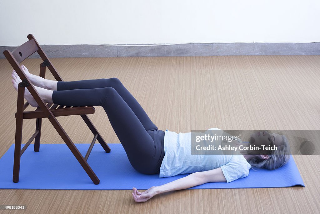 Mature woman resting legs on chair