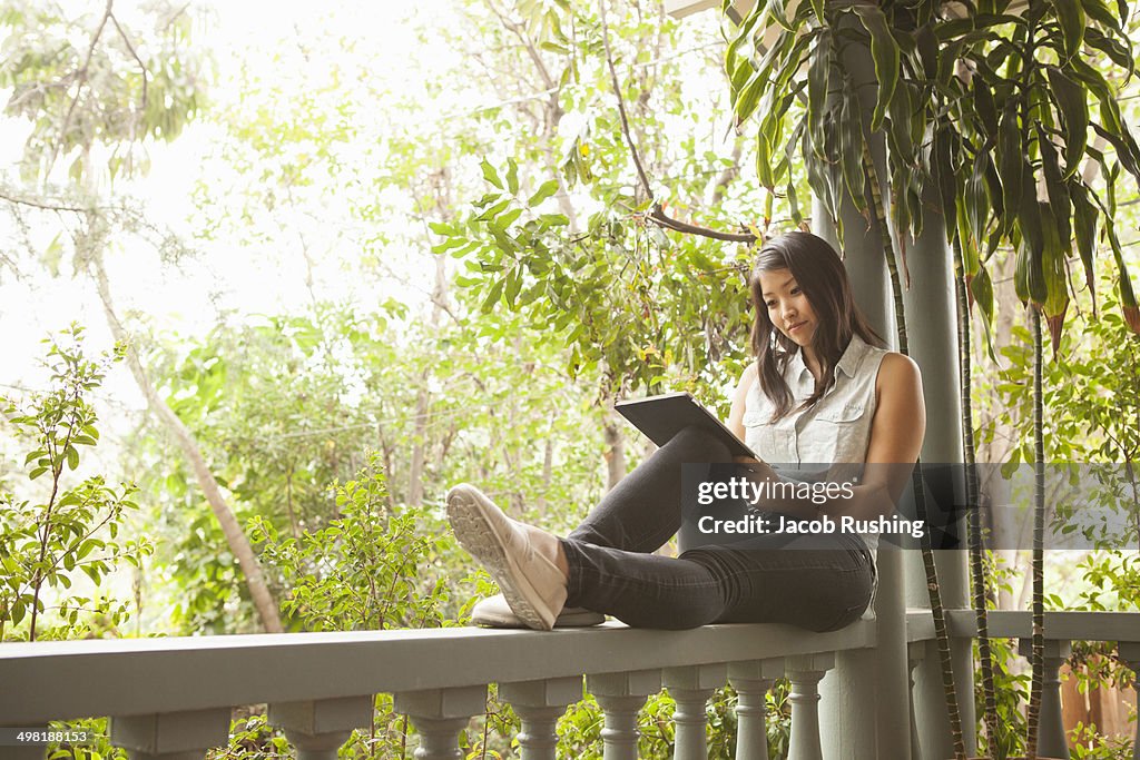 Young woman using digital tablet on porch