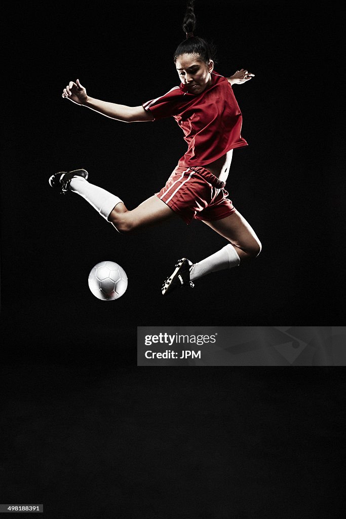 Young woman jumping for football