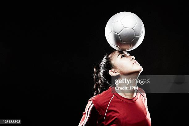 young woman balancing football on forehead - woman football stock-fotos und bilder