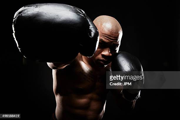 boxer with black boxing gloves punching towards camera - faustschlag stock-fotos und bilder