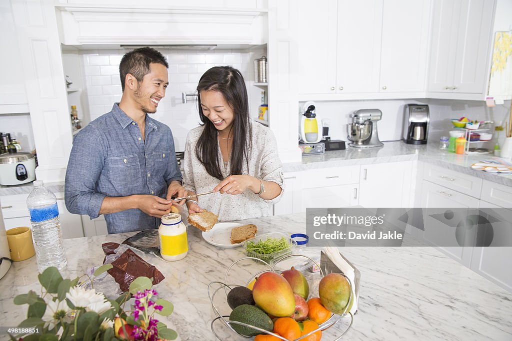 Mid adult couple preparing sandwich in kitchen