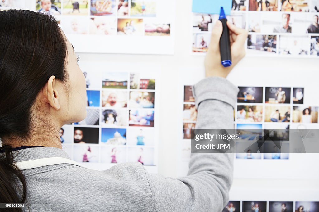 Young woman looking at photographs holding pen