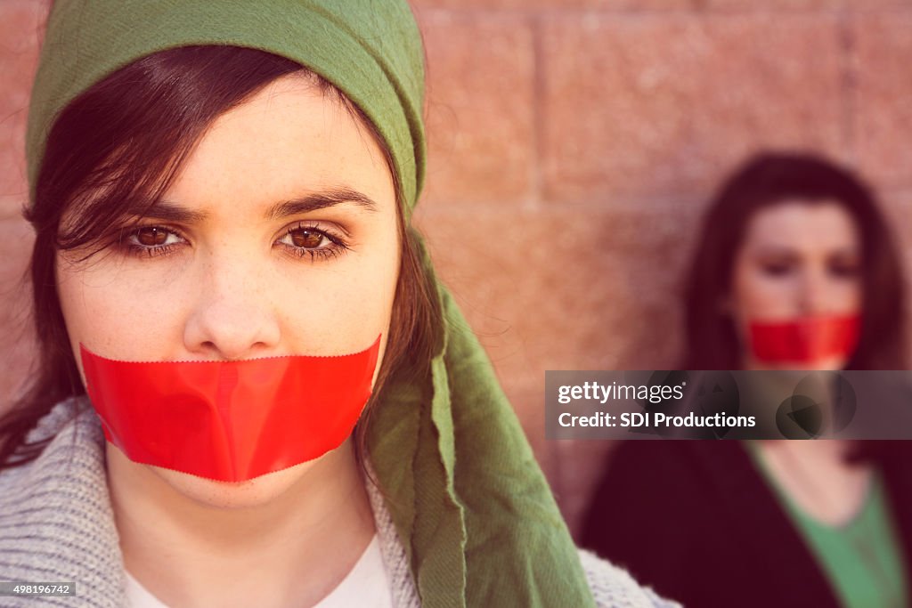 Young women with red tape over mouths in protest