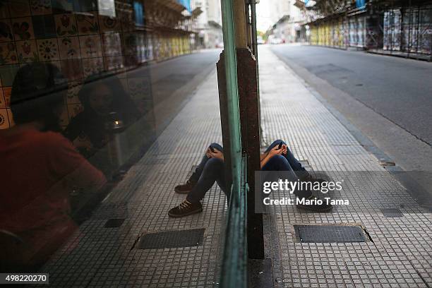 People sit in a cafe as a woman uses her phone on the sidewalk on November 21, 2015 in Buenos Aires, Argentina. Argentina is facing its first...