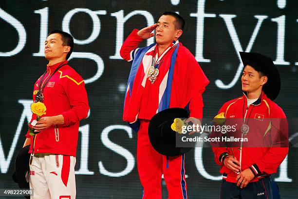 Jingbiao Wu of China, Yun Choi Om of North Korea and Kim Tuan Thach of Vietname pose on the podium after leading the total scores in the men's 56kg...