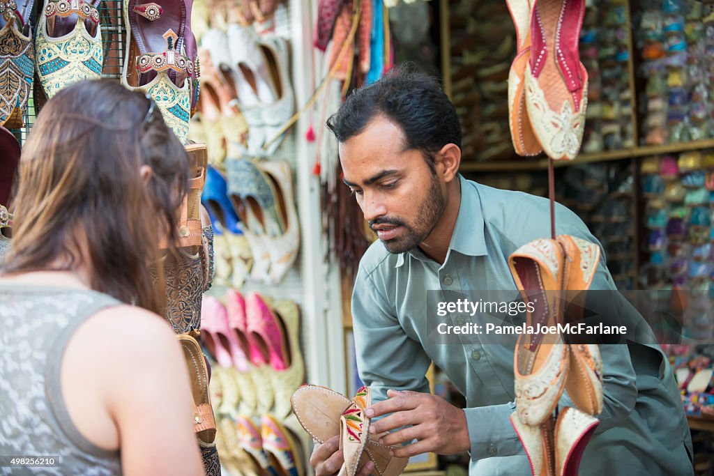 Salesman Showing Shoes to Woman Shopping at Souk, Dubai, UAE