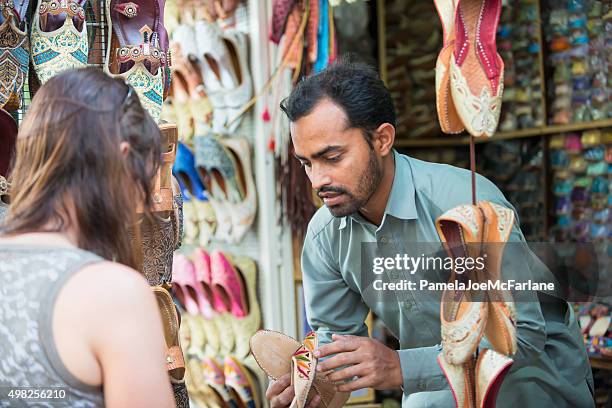 vendedor mostrando sapatos para mulher de compras na feira árabe ao ar livre, dubai, eau - shoe seller imagens e fotografias de stock