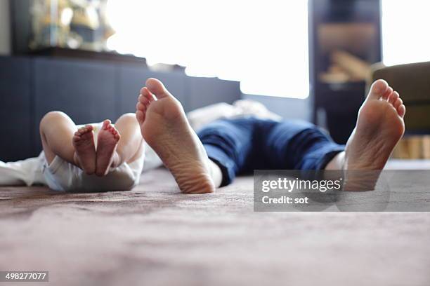 foot of mother and baby lying on carpet - barefeet stock-fotos und bilder