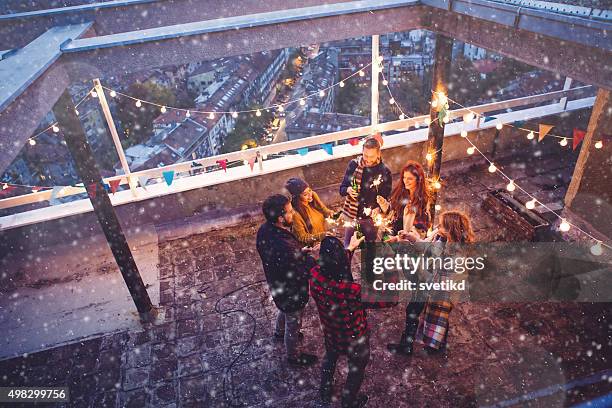 group of friends at rooftop party - woman snow outside night stockfoto's en -beelden