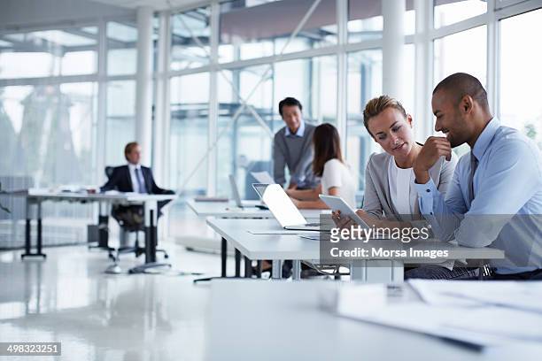 colleagues discussing over digital tablet - corporate business foto e immagini stock