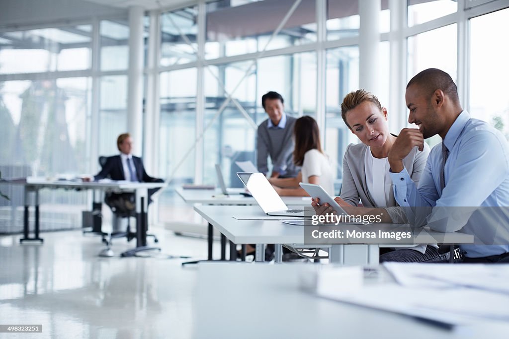 Colleagues discussing over digital tablet
