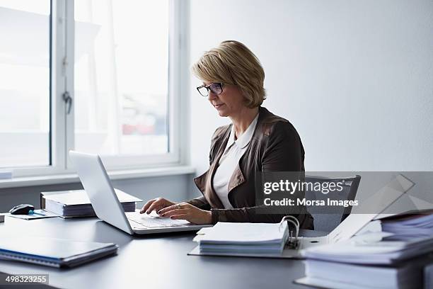 businesswoman using laptop in office - working computer stock-fotos und bilder