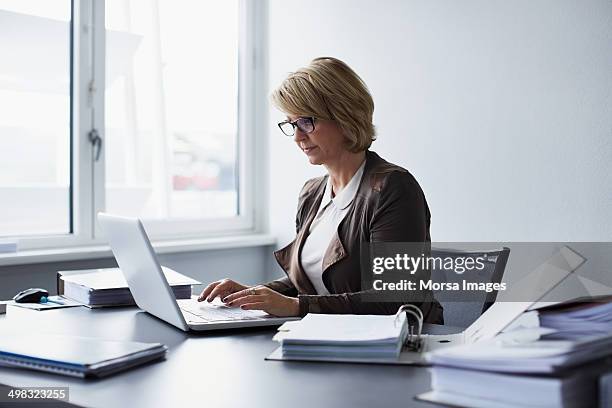 businesswoman using laptop in office - one mature woman only ストックフォトと画像