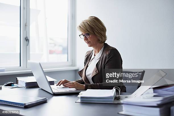 businesswoman using laptop in office - werken stockfoto's en -beelden