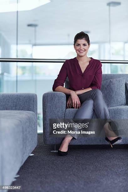 confident businesswoman sitting on sofa - legs crossed at knee stock pictures, royalty-free photos & images