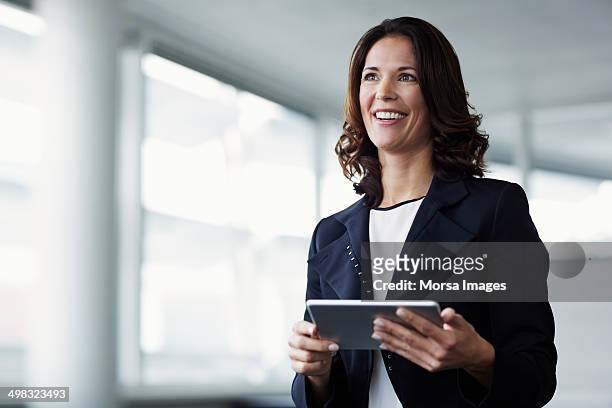 happy businesswoman holding digital tablet - looking away stock-fotos und bilder