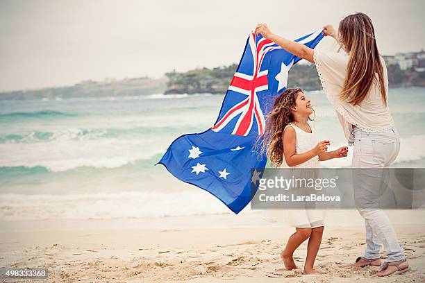 mother and daughter with australian flag at the beach - australia day stock pictures, royalty-free photos & images