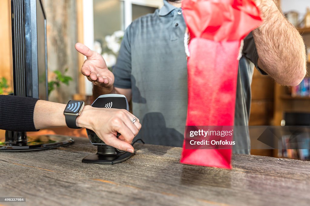 Frau bezahlen mit NFC-Technologie auf Smart Watch im Store