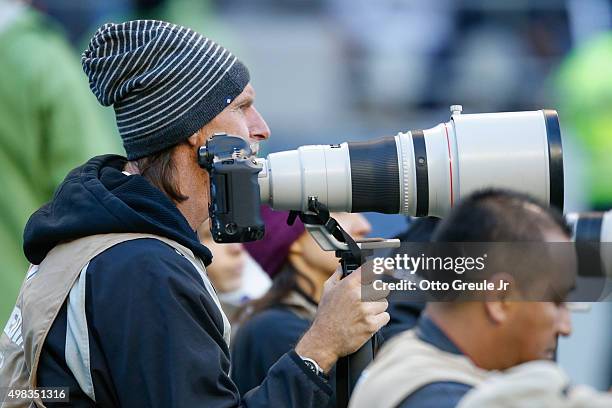 Former Major League baseball pitcher Randy Johnson photographs from the sidelines during the game between the San Francisco 49ers against the Seattle...
